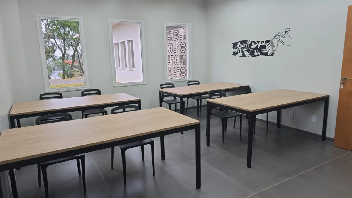 Sala de aula com mesas coletivas e cadeiras empilháveis